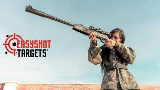 woman outdoors aiming shotgun at target