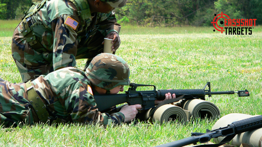 Two military personal, one lying on the floor looking through the sight hole